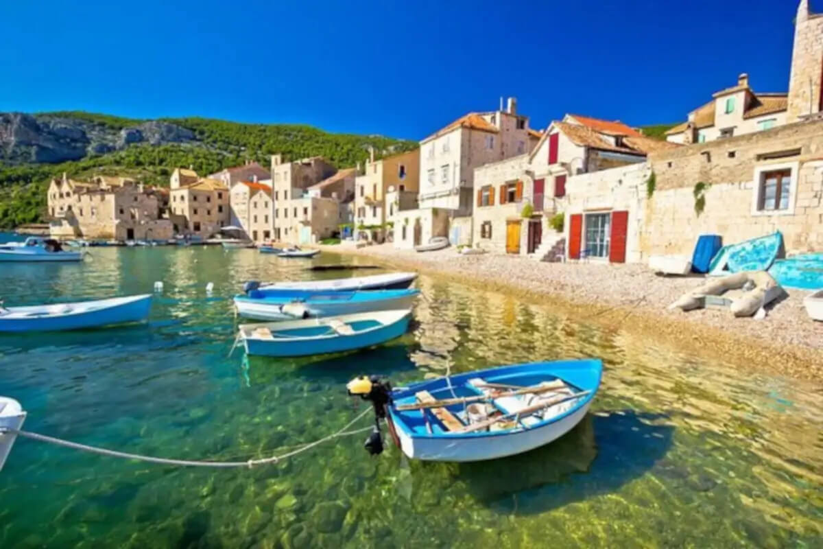 Fishing boats anchored on the shallow beach with little fishermen houses in Komiza